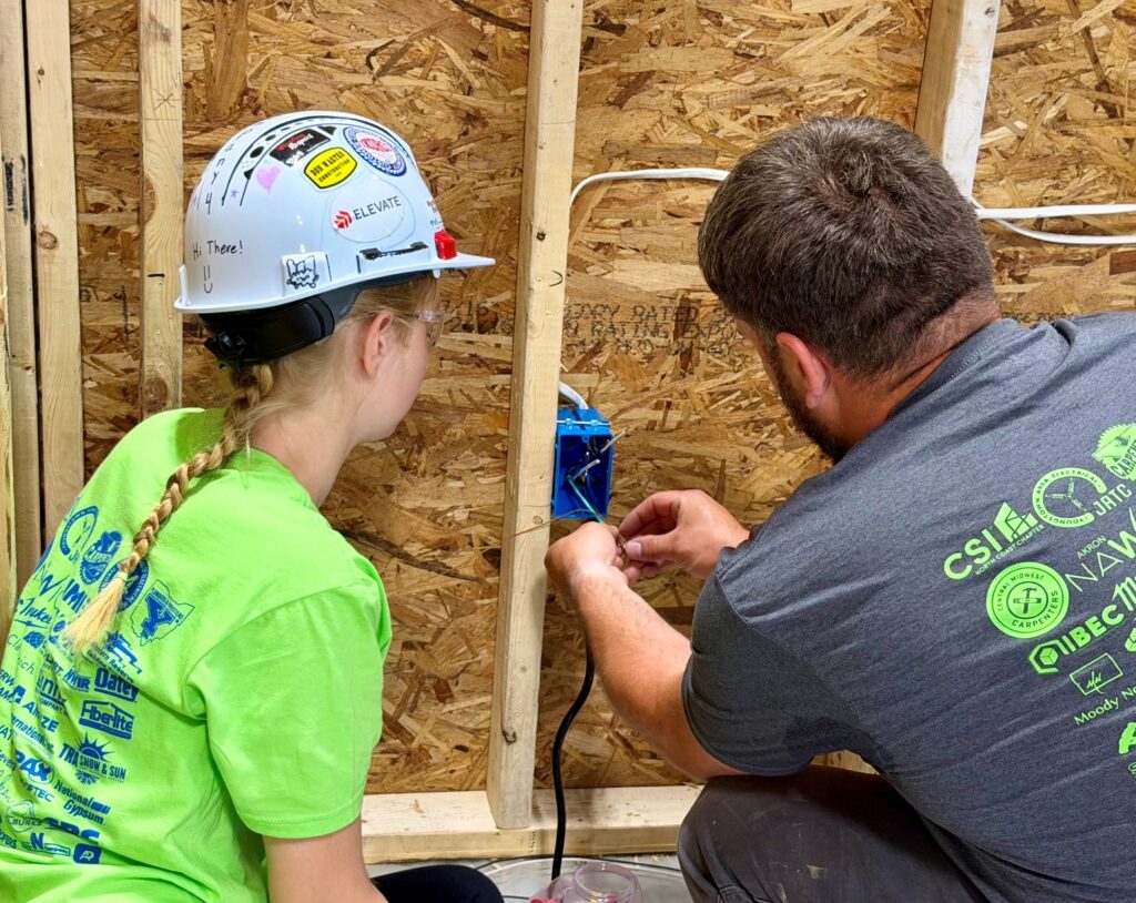Chris Platton, of Gulu Electric, helps student with wiring on electrical project for LBCC Camp. 