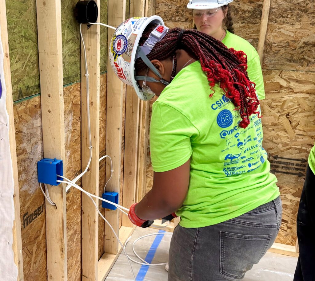 Student works on pulling wire for light switch, outlet and light bulb at LBCC Camp.
