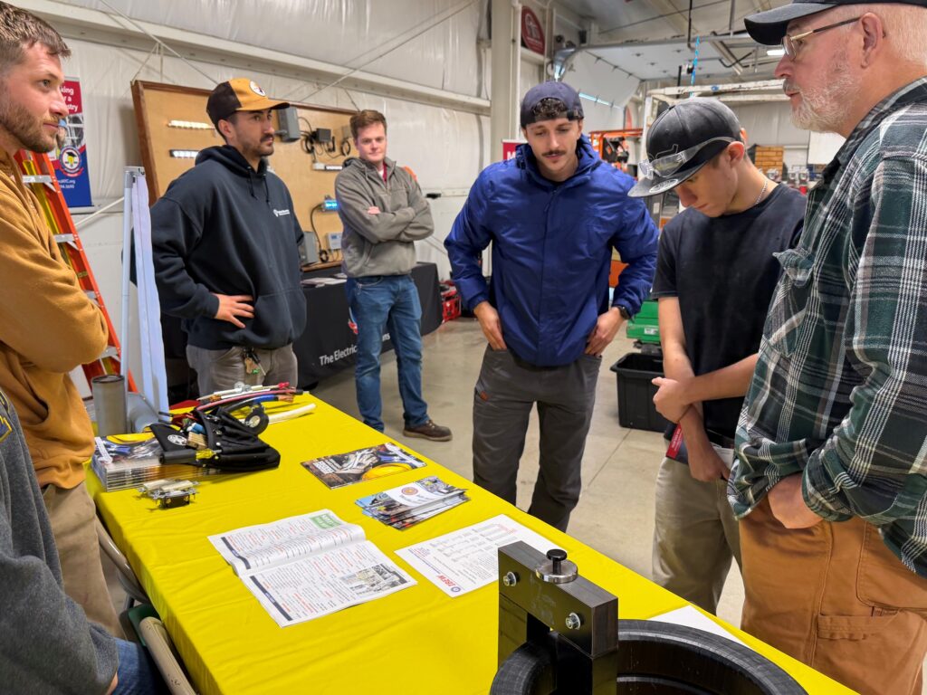 Students and dad talking with JATC apprentices about opportunities in the electrical trade.