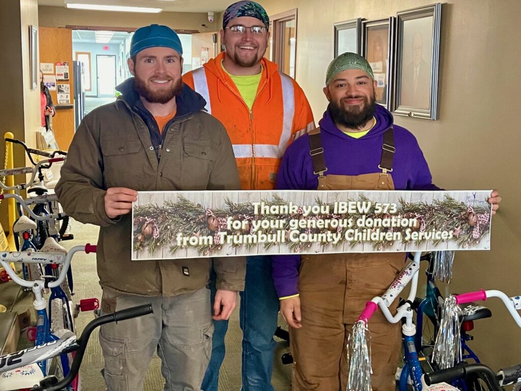 Local 573 fifth-year apprentices Wyatt Baer, Luke Culp and Sean Duckworth at Trumbull County Children Services holding a thank you sign after dropping off bikes to the agency.