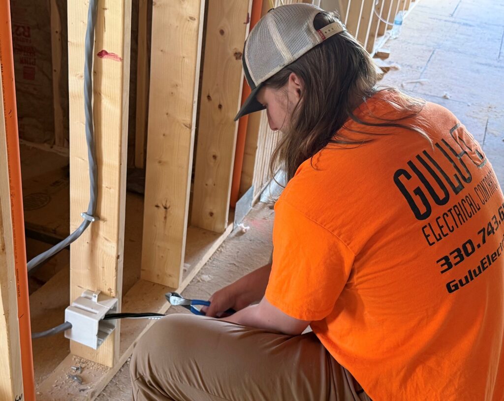 Michael Gushura, second-year apprentice with Gulu Electric, working on wiring for outlet at Grace Village Apartments.