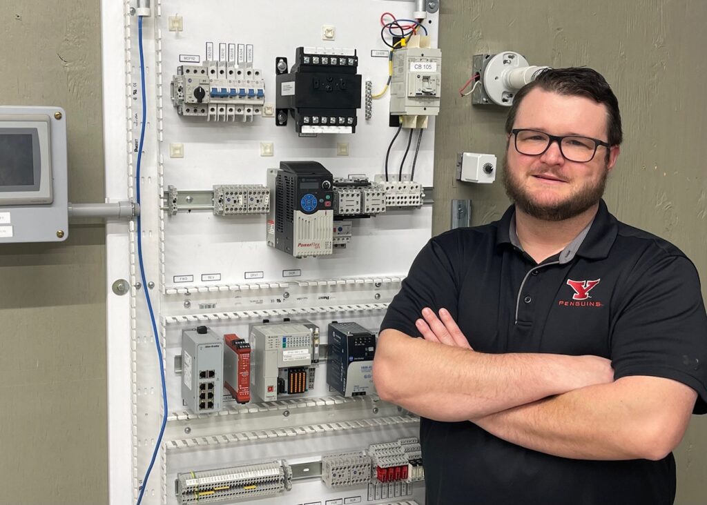 Ahren Peplow in the Youngstown JATC lab next to the motor control board used to train electricians.