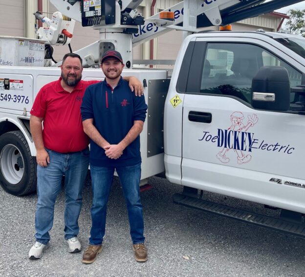 Eric Carlson, president of "Joe" Dickey Electric, with Alex Birtalan, junior estimator at Dickey Electric, outside truck at the office.