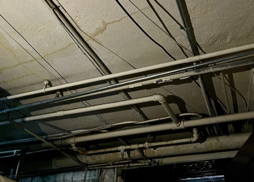 Concrete ceiling in the basement poses a challenge for CR Electric. Electricians will use conduit along the ceiling and strategize how to run the new wiring.