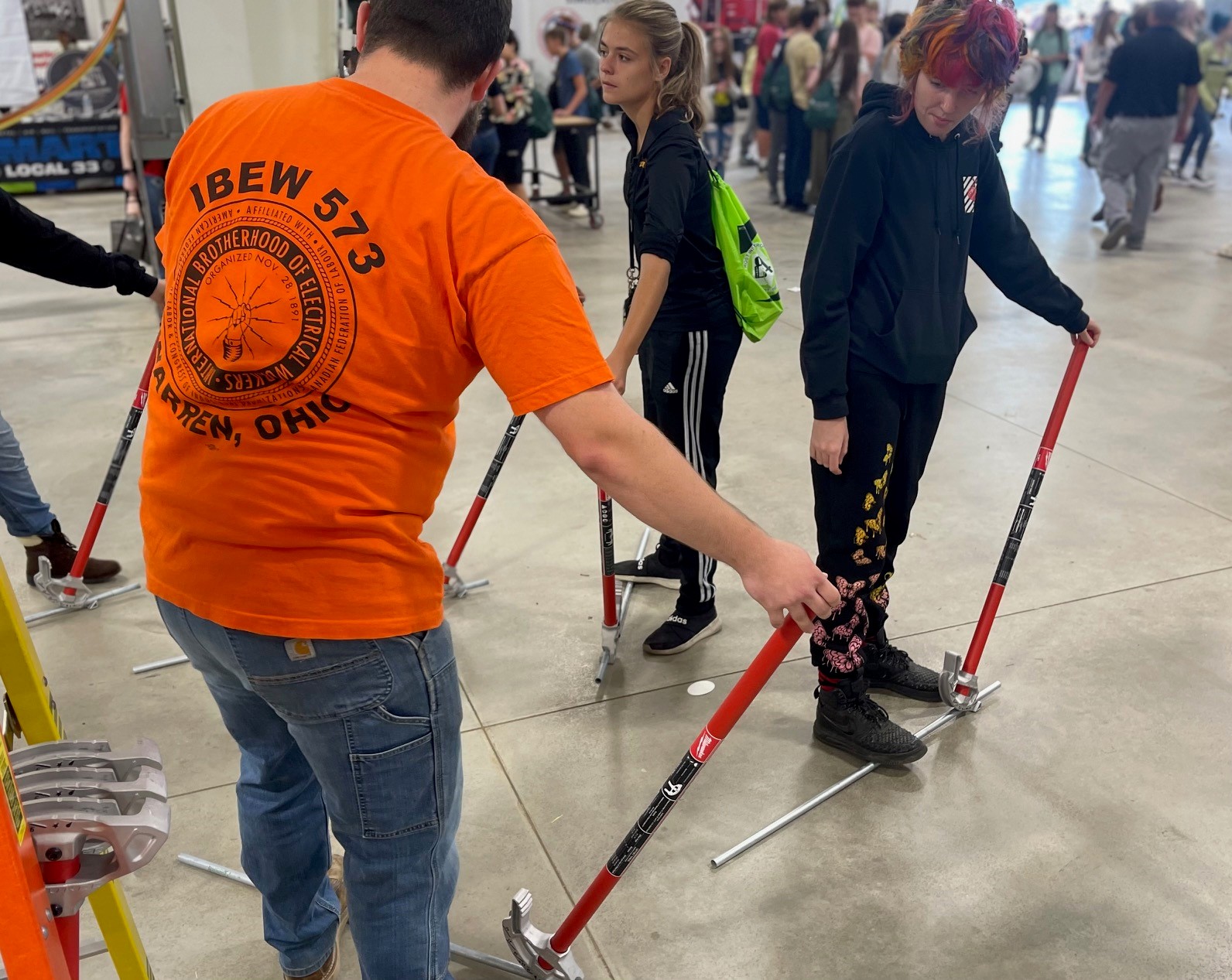 IBEW Local 573 apprentice showing students at Mahoning Valley Skilled Trades Expo how to bend conduit.