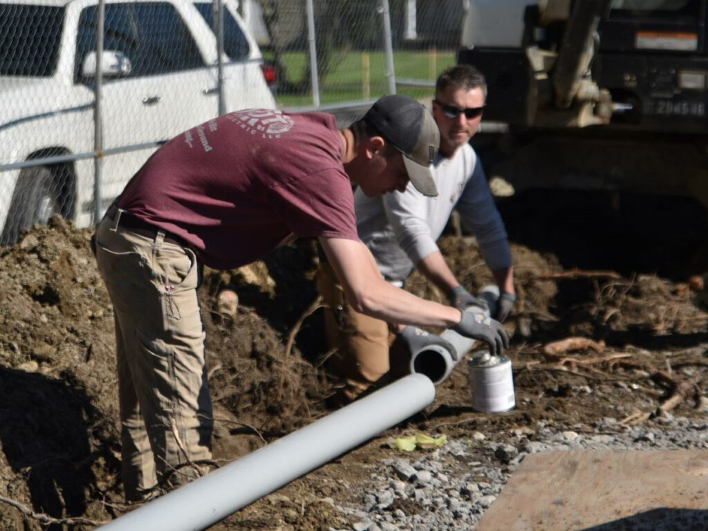 Electricians install pipe underground.