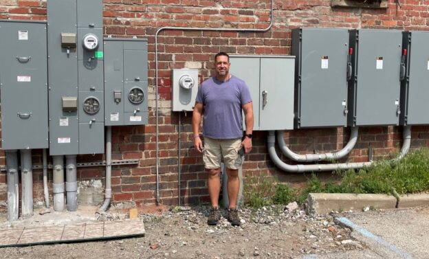 Greg DeMatteo Santon Electric project manager stands outside power boxes behind Gallagher Building