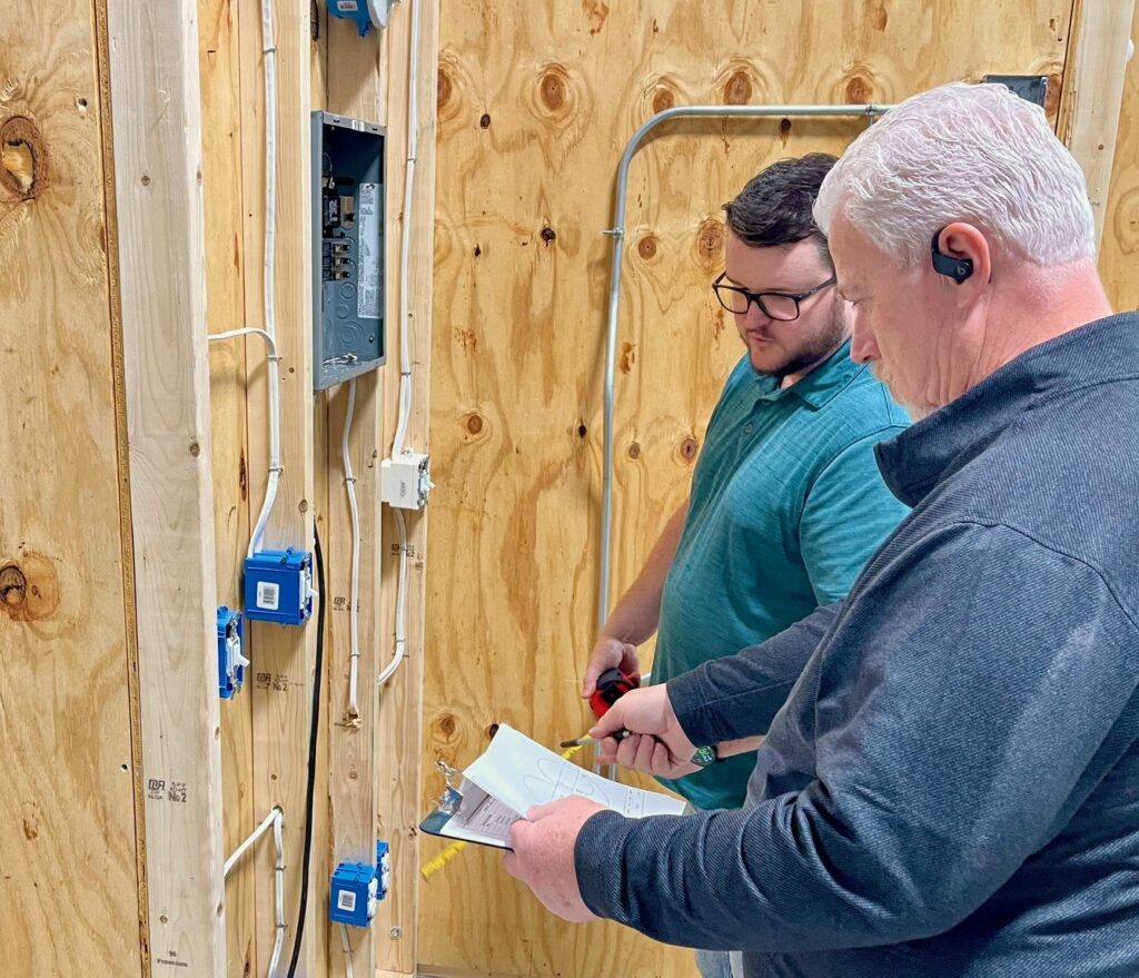 Eric Davis, Warren JATC training director, and Ahren Peplow, Youngstown JATC training director judging competitors' work for the residential wiring project.