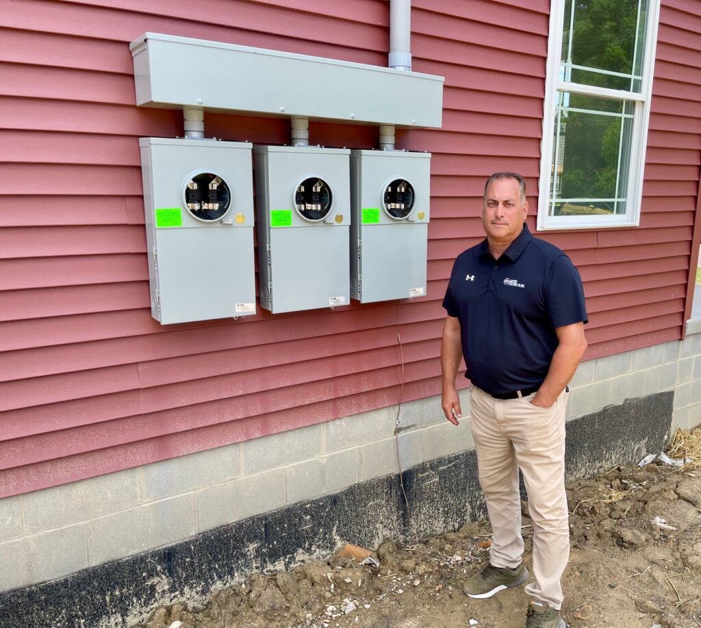 Frank Sferra, of Santon Electric, stands by electrical service boxes at residential housing duplex on Glenwood Avenue in Youngstown