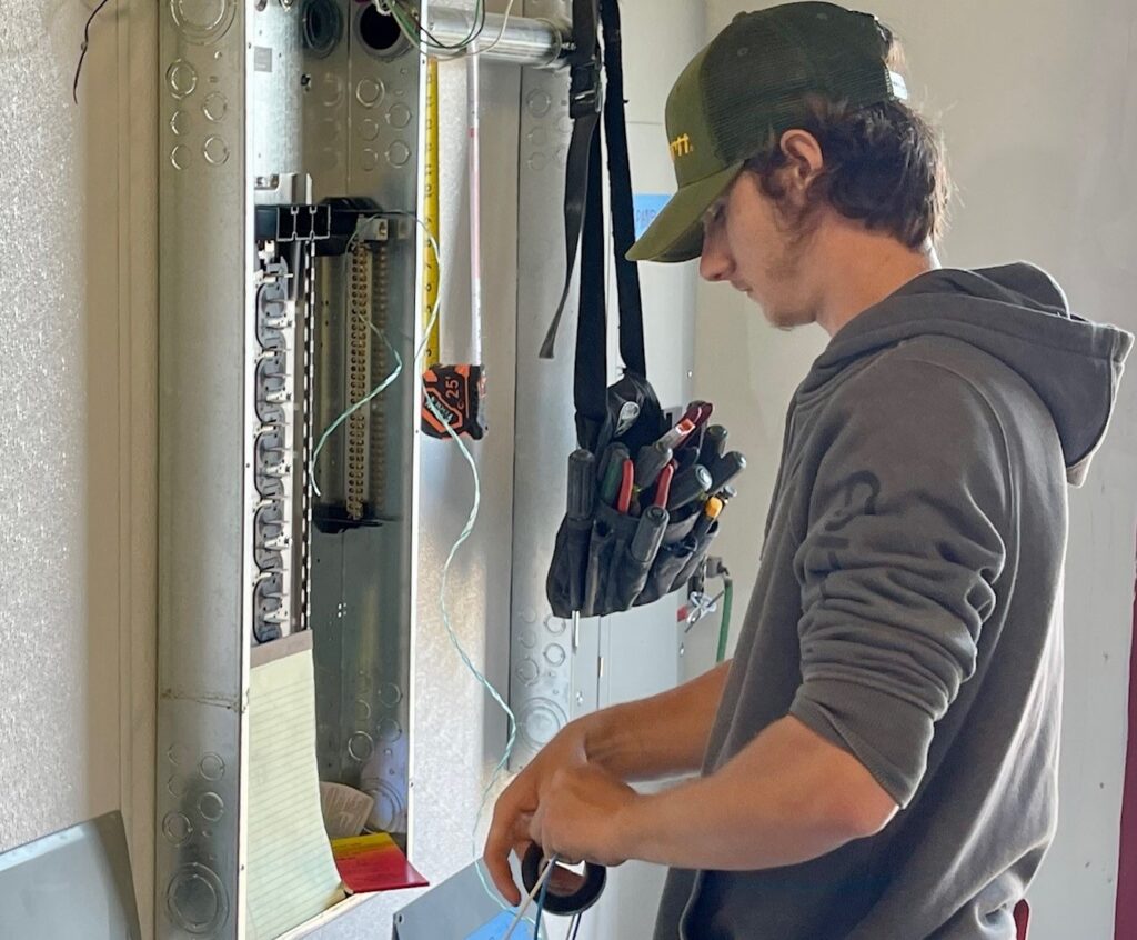 Ivan Lindberg working on the new electrical panel inside the Insomnia Cookie on YSU campus during his first-ever job as a CW worker.