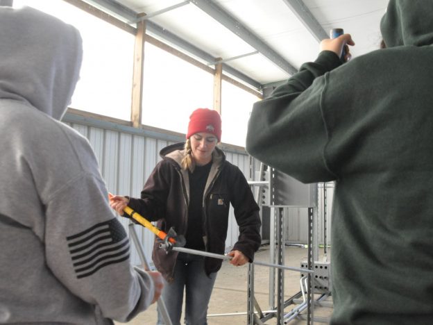 Electrical apprentice shows high school students how to bend conduit.
