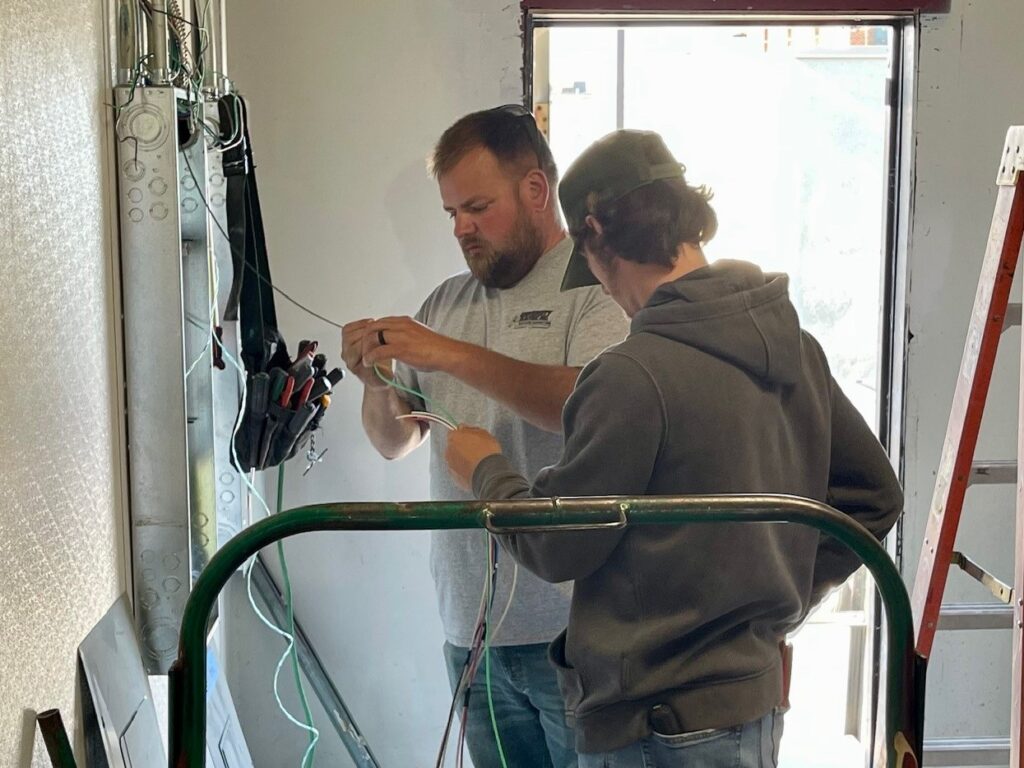 Mike Engle and Ivan Lindberg, from University Electric, working on new electrical panel for Insomnia Cookies on YSU campus.