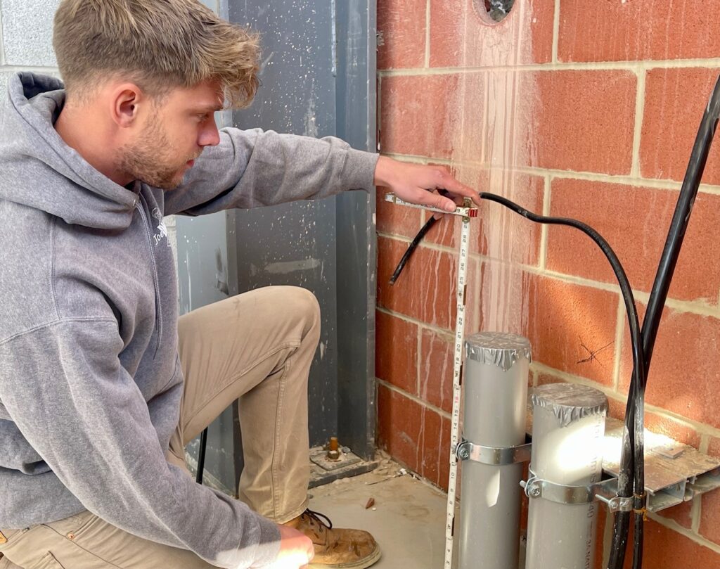 Tom Plummer measures a main feed pipe in the electrical room of the facility.