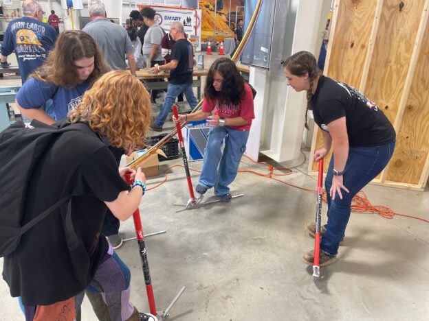 Apprentice Grace Morrison helps students bend conduit at the Mahoning Valley SKilled Trades Expo.